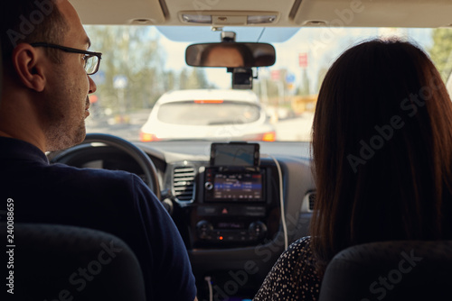 Young European couple is staying in a traffic jam, they are searching for another way, using the navigator. © Artem