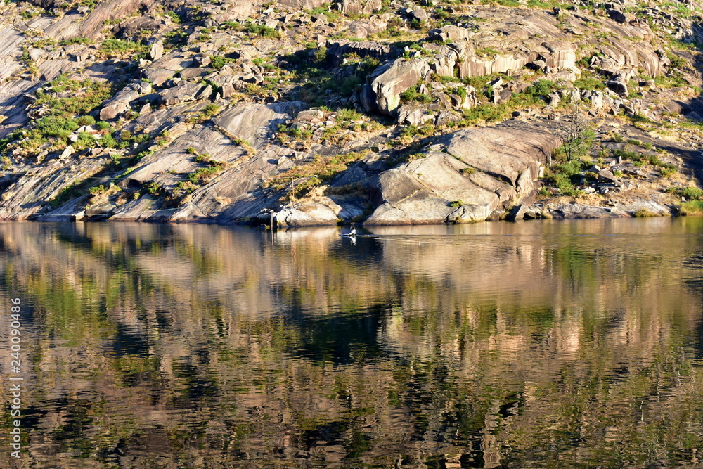 Mountain and river with water reflections and man in kayak. Sunset light. Ezaro, Galicia, Spain. Mountain and river with water reflections and man in kayak. Sunset light. Ezaro, Galicia, Spain.