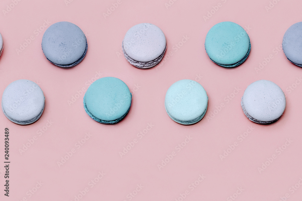 Fototapeta premium Colorful macarons or macaroons on pink paper background top view. Minimalistic flat lay composition