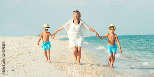 Family walking on the beach Mother and two sons.	