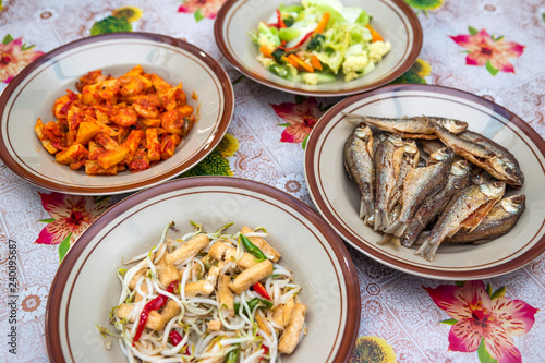 Assorted Indonesian home made food served on plates : kentang balado, sayur cap cay, ikan goreng, tumis toge tahu