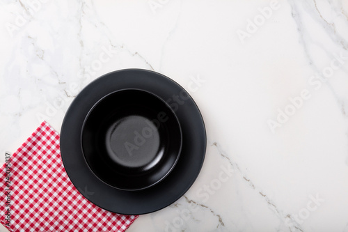 Black Soup Bowl on marble countertop with red plaid napkin.