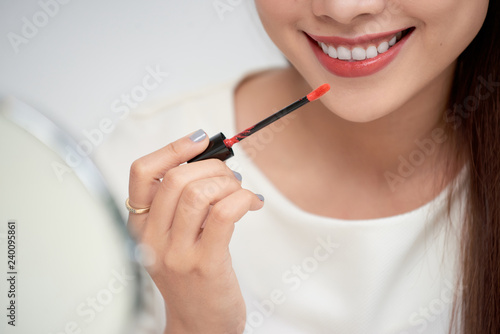 Young beautiful woman professional beauty vlogger or blogger applying lipstick cream to her mouth, doing a make up tutorial