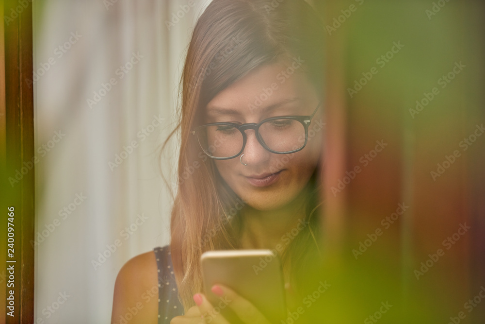 Young woman using smart phone indoors. Window reflection from outdoors. Young woman using smart phone indoors. Window reflection from outdoors.
