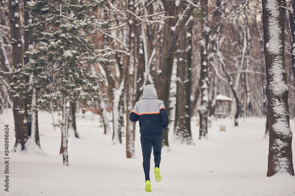 Man jogging in a cold winter snowy day outdoors.