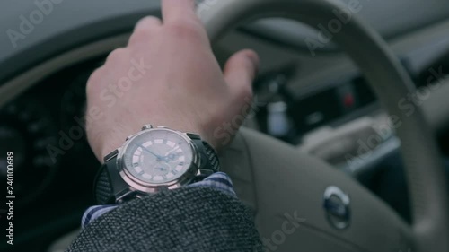 Driver looks at his watch in the car