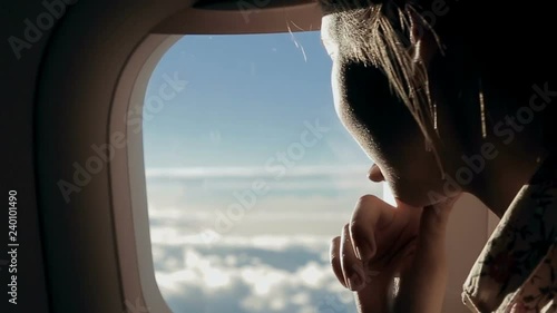 Girl looks at the clouds from airplane window