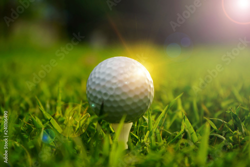 Blurred golf ball on tee in beautiful golf course at sunset background.