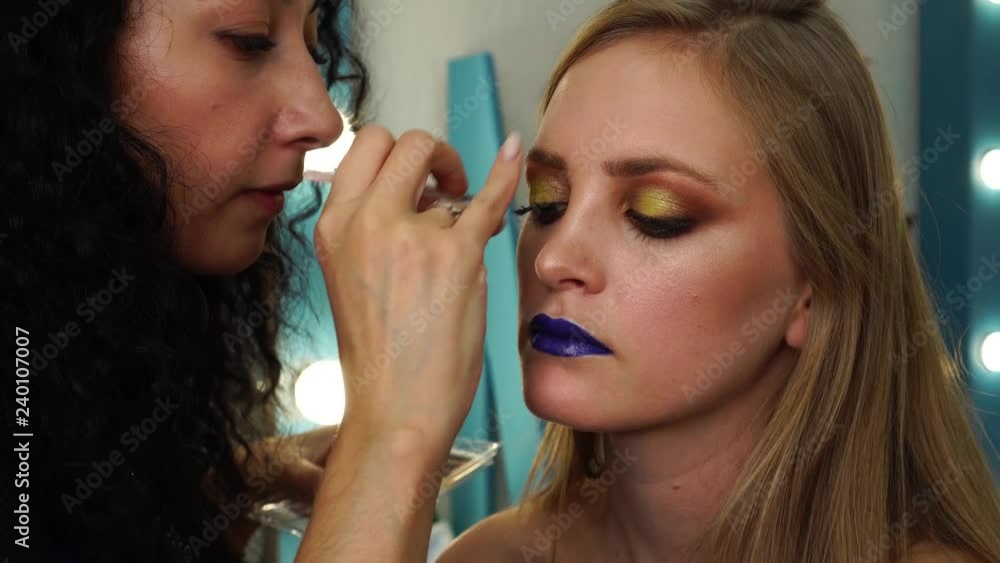 Close up view on process of applying fake eyelashes with glue and tweezers on eyes to complete party makeup look Close up view on process of applying fake eyelashes with glue and tweezers on eyes to complete party makeup look