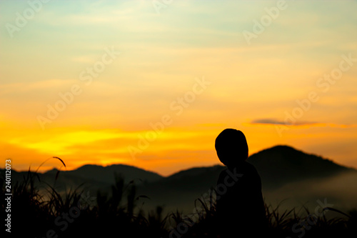 Blurry morning sun light behind the mountains with the shadow of a woman and the tree.