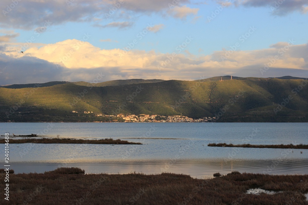 Background view of Menidi village in Aitoloakarnania at the shore of Ambracian (Amvrakikos) gulf green hills mountains shadows of the clouds from the Koprena lighthouse in Greece
