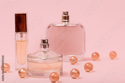 Women perfumes with glass balls on a pink background.