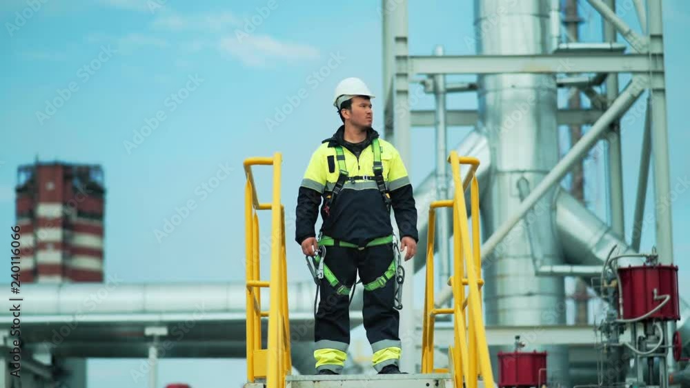 Confident male metal worker standing on tower and looking on territory of large factory Confident male metal worker standing on tower and looking on territory of large factory