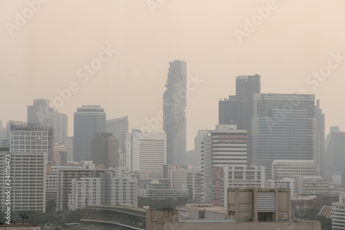 Air pollution effect made low visibility cityscape with haze and fog from dust in the air during sunset in Bangkok, Thailand. Image contain noise and grain. © artitwpd
