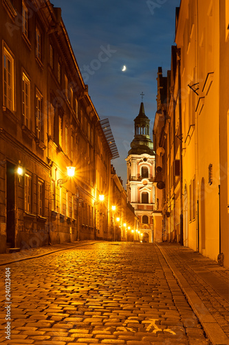 Valokuva A cobbled street with a baroque belfry of a historic monastery at night in Poznań
