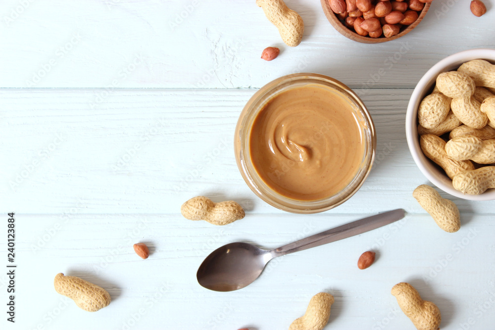 creamy peanut butter in a glass jar and peanuts beans on wooden background top view creamy peanut butter in a glass jar and peanuts beans on wooden background top view
