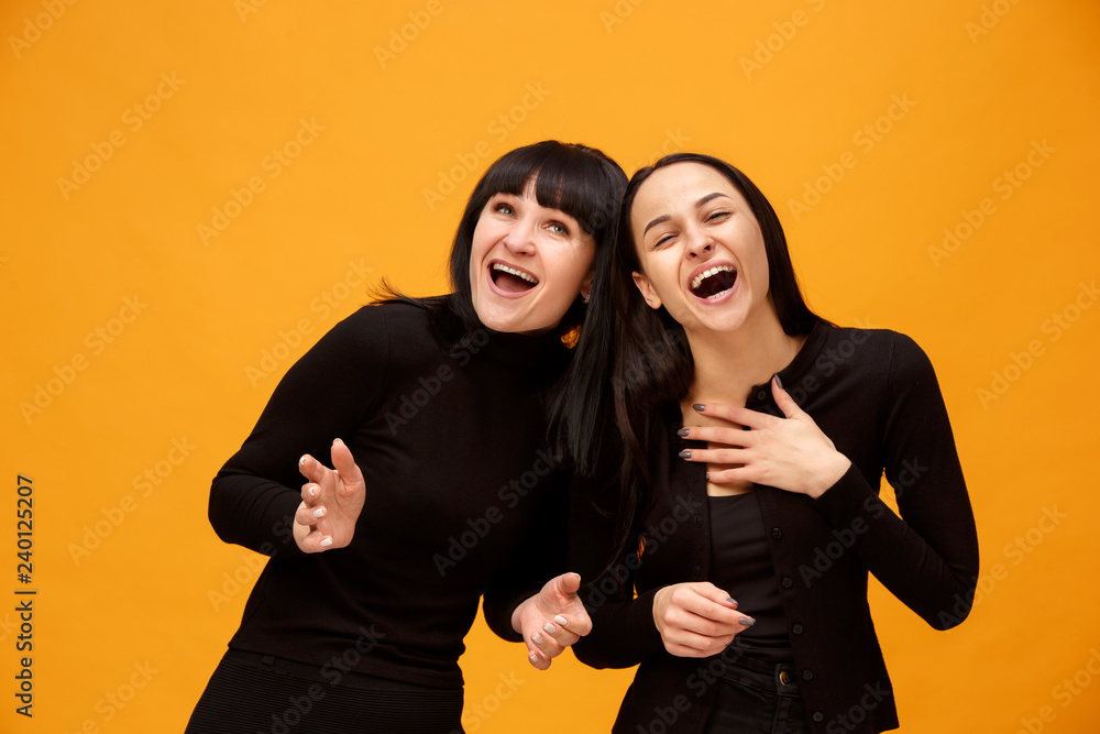 A portrait of a happy smiling mother and daughter at studio on gold background. Trendy colors. Human positive emotions and facial expressions concept A portrait of a happy smiling mother and daughter at studio on gold background. Trendy colors. Human positive emotions and facial expressions concept