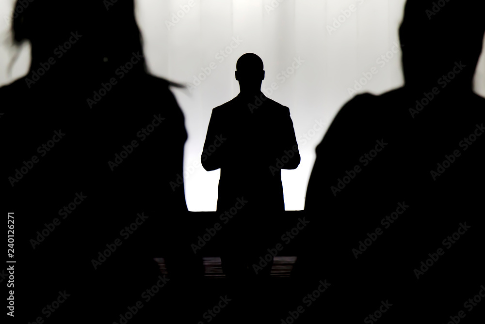 Silhouettes of a mystery man standing , watching and confronting two blurry persons