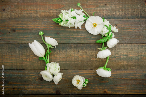 Floral frame with white flowers and green leaves isolated on wooden background. Flat lay  top view