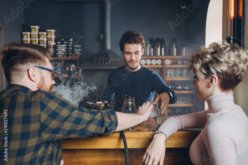 young stylsh man taking a glass from barmen. close up back view shot photo