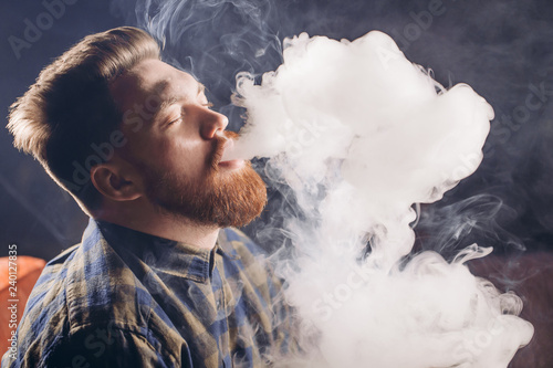 young relaxed man with red beard is inebriated by tobacco. close up side view shot