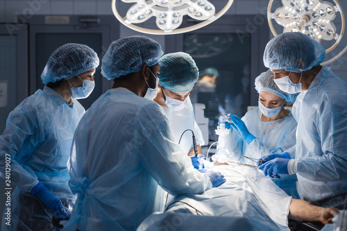 Group of concentrated surgeons engaging in rescue of male patient in operation room at hospital, emergency case, surgery, medical technology, health care and disease treatment concept