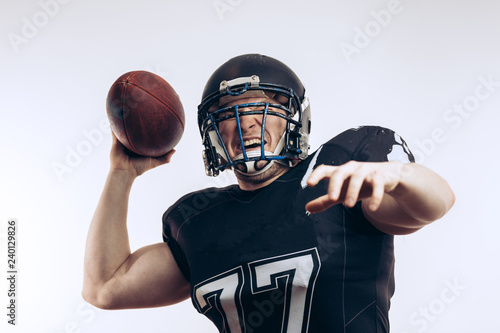 American football player wearing black helmet and jersey serving the ball in motion isolated over white background