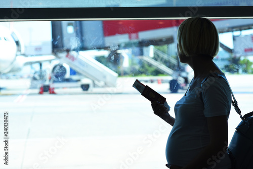 Pregnant woman is traveling by plane standing near the window