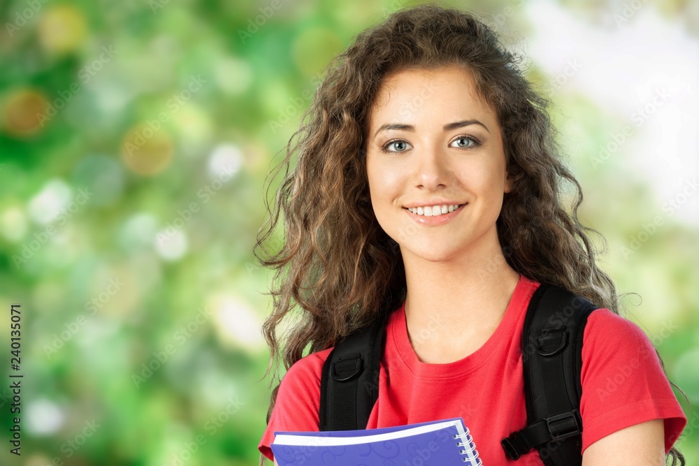 Fototapeta premium Portrait of a cute young student girl holding colorful notebook