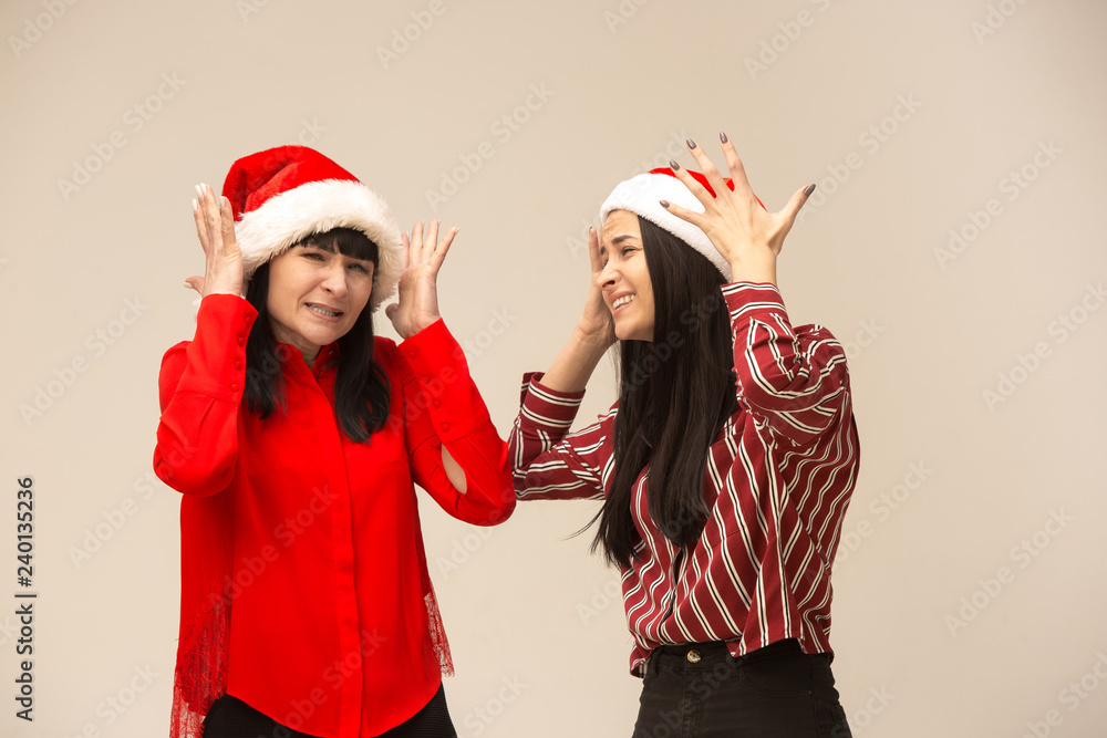 Happy family in Christmas sweater posing. Enjoying love hugs, holidays people. Mom and doughter on a gray background in the studio Happy family in Christmas sweater posing. Enjoying love hugs, holidays people. Mom and doughter on a gray background in the studio
