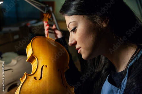 Fotografie young woman apprentice violinmaker checking her violin