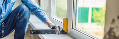 Man in a blue shirt does window installation BANNER, LONG FORMAT photo