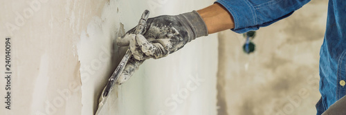 Foto master is applying white putty on a wall and smearing by putty knife in a room o
