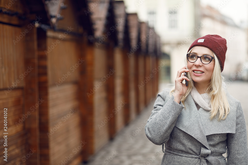 Fototapeta premium Beautiful woman walking in the city streets and using modern smartphone.