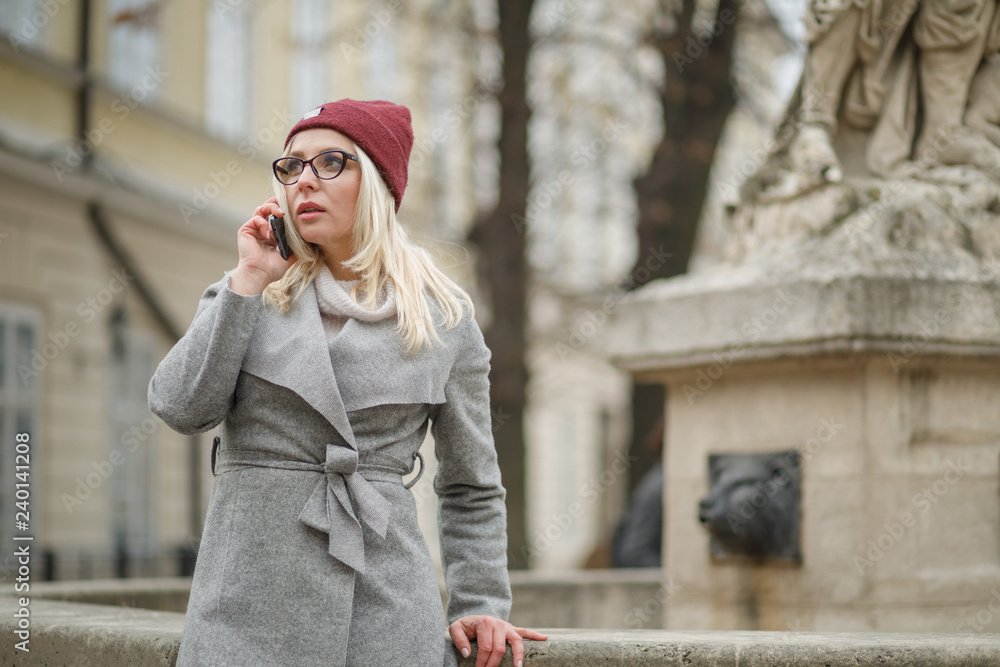 Fototapeta premium Beautiful woman walking in the city streets and using modern smartphone.