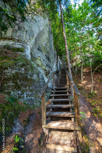 tourist trail with wooden pathwalk and stairs near sandstone cliffs