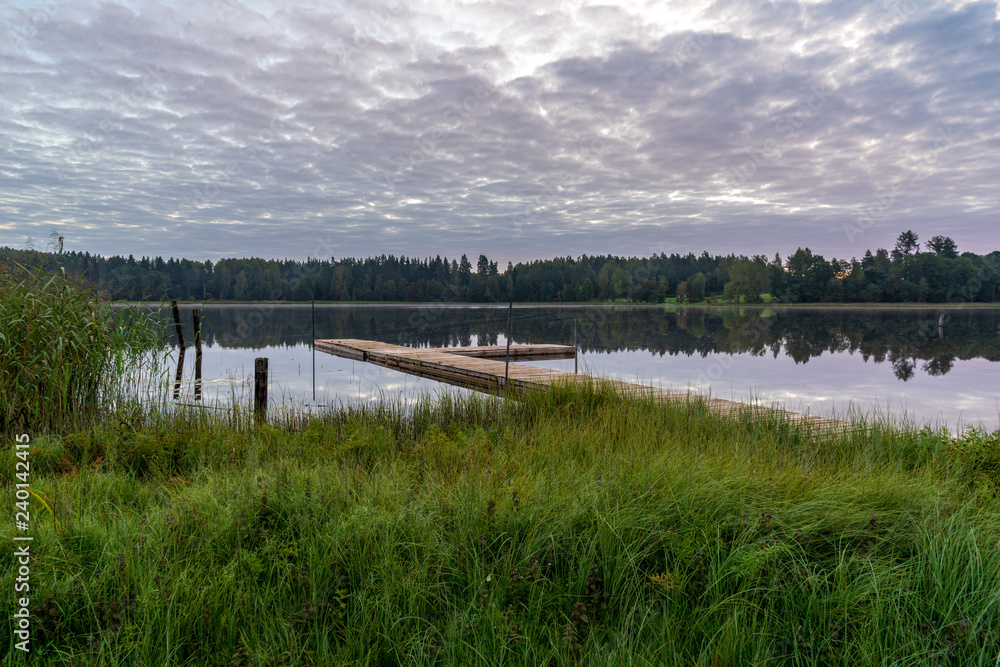 Obraz premium picnic area by the lake with wooden plank boardwalk