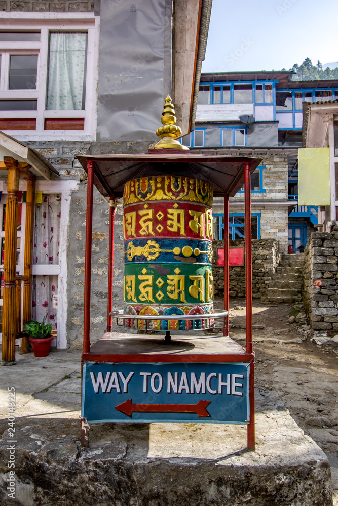 Close up view of colorful prayer wheel. Pedestrian sign to Namche Bazaar. Sagarmatha (Everest) National Park, Nepal.