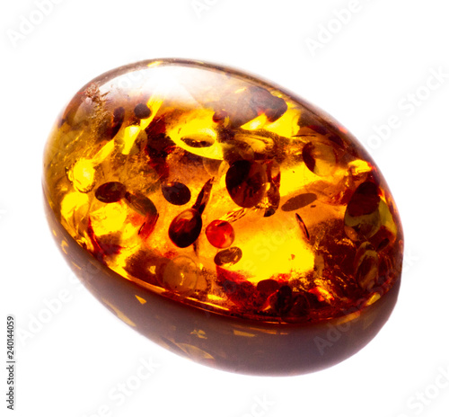 Polished cabochon of artificial amber with inclusions on white background isolated