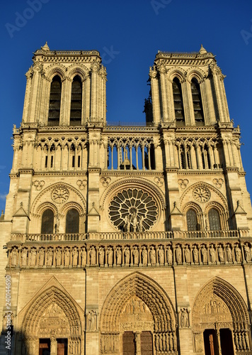 Notre Dame Cathedral, facade with sunset light. Paris, France, sunny day, blue sky.