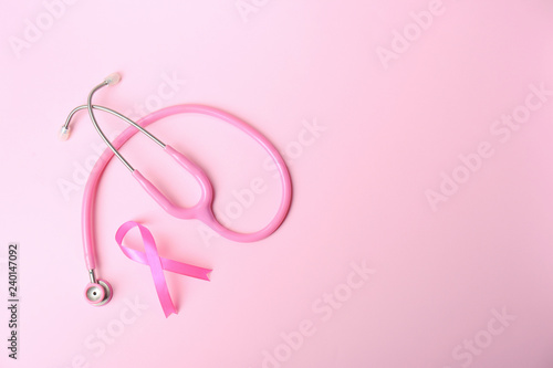 Pink ribbon and stethoscope on color background, top view with space for text. Breast cancer concept