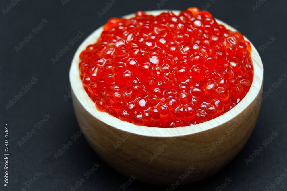 Closeup macro saucer or bowl with slide of fresh tasty red salmon caviar on black background. Top view. Concept gourmet snack seafood appetizer Closeup macro saucer or bowl with slide of fresh tasty red salmon caviar on black background. Top view. Concept gourmet snack seafood appetizer