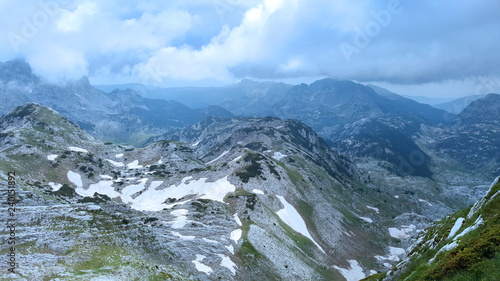 Top of the mountain view of the mountain peaks and rocky valley covered in snow