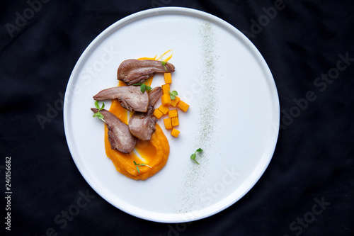 beef tongue cut into pieces with pieces of orange pumpkin lies on a white plate