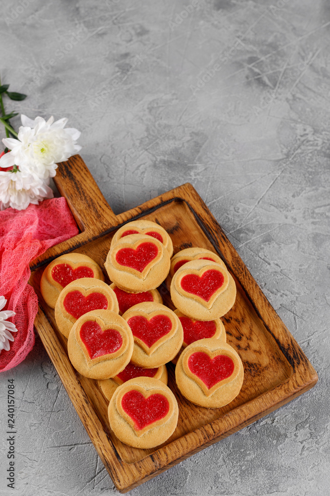 Heart-shaped cookies filled with chrysanthemum flowers on a wooden board. Concept for Valentine's Day.