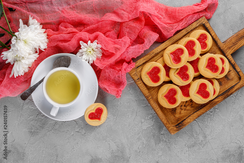 Flat lay. Cup with tea and cookies with a heart on a decorative board is an ornament of fresh flowers. Valentine's day concept. Flat lay. Cup with tea and cookies with a heart on a decorative board is an ornament of fresh flowers. Valentine's day concept.
