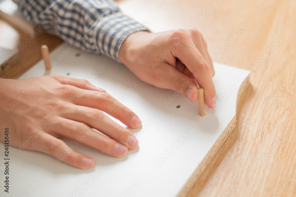person installing new furniture in his accomodation on wooden floor а