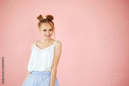 Close-up portrait smiling beautiful girl with funny hairstyle on a pink background. spring fashion for teens.