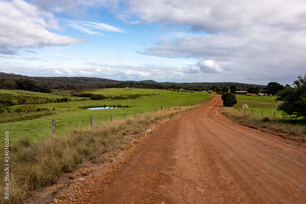 A red dusty road in Warren National Park in Western Australia with nice green landscape