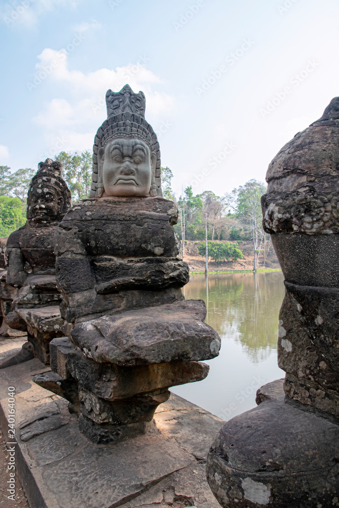 One of the Stone Asuras holding the nāga Vasuki on a bridge leading into the 12th century city of Angkor Thom. One of the Stone Asuras holding the nāga Vasuki on a bridge leading into the 12th century city of Angkor Thom.